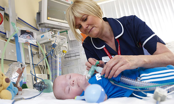 A children’s nurse tends to an infant on a hospital ward