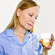 A young nurse in a santa hat drinking a glass of wine on a white background