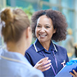senior nurse with junior student in busy hospital corridor