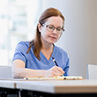 A mature adult female doctor or nurse spends time updating a patient's medical chart.