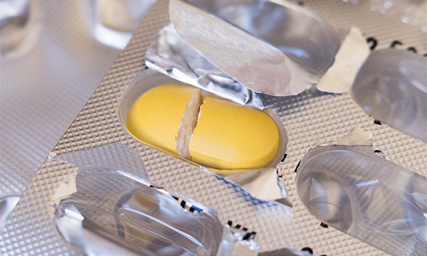 A yellow split tablet in a blister pack