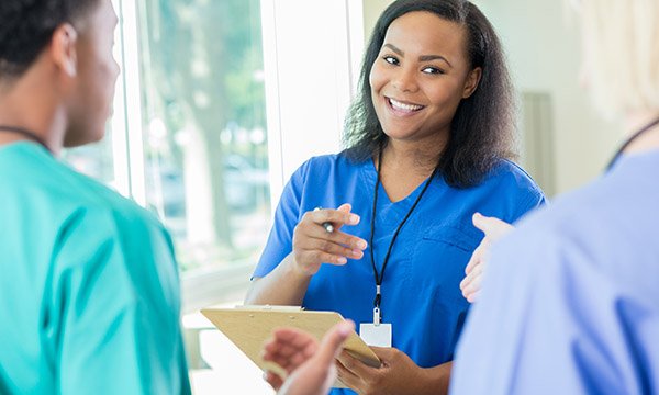 Relational leadership: a senior nurse smiles while talking warmly with two team members