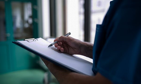 A nurse writing notes on a clipboard