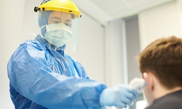 Picture shows a medic in protective clothing checking a boy's temperature.&nbsp;NICE is reviewing its critical care scale amid concerns that people with learning disabilities could be denied intensive care.