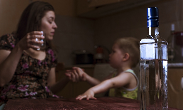 Woman drinking alcohol while talking to small child